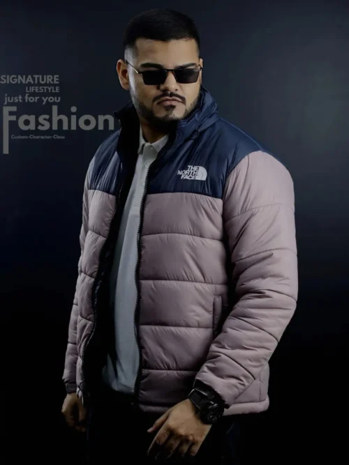 A man wearing The North Face navy blue and mauve two-tone hooded puffer jacket with black sunglasses, high-quality winter apparel for men in Bangladesh.