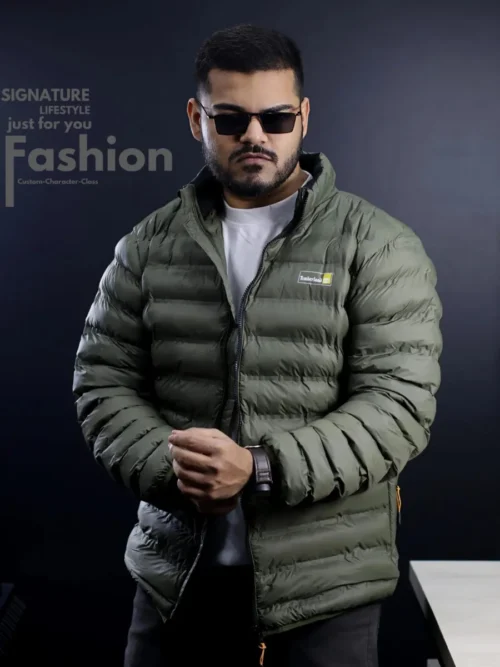 A man modeling a premium Timberland lightweight quilted puffer jacket in olive green featuring a stand-up collar and black front zipper detail.