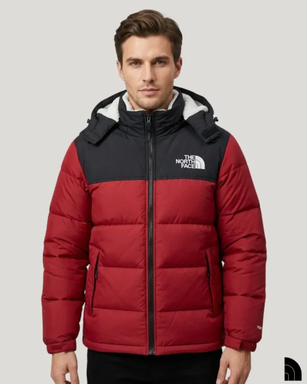 A man wearing a red puffer jacket with a black shoulder yoke and high, fleece-lined collar.
