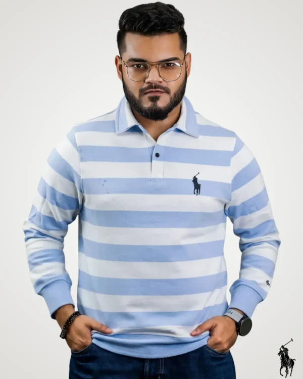Front view of a young man wearing a light sky blue and white full sleeve striped polo shirt, featuring a casual button-down collar, fitted cuffs, and a contrasting chest logo emblem.