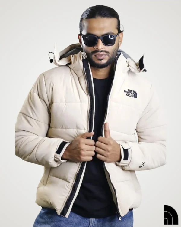 A stylish man wearing an unzipped khaki 700 fill sherpa fleece jacket over a black t-shirt. This heavy-duty hooded winter puffer jacket showcases a cozy insulated design, detailed chest embroidery, and premium warmth for cold weather protection.