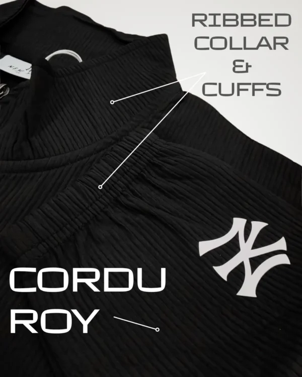Detailed macro view of a black men's corduroy shacket highlighting the structured ribbed collar and snug ribbed cuffs. The image clearly displays the rich, warm texture of the corduroy fabric and a partial white logo, essential features of this trendy outerwear.