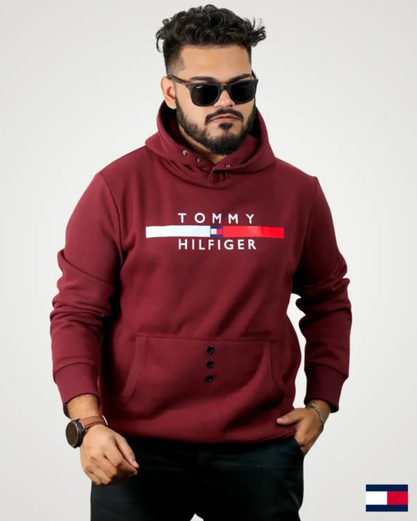 A young man in a deep maroon snap button hoodie men design, featuring snap closures at the high-neck collar, white and red block typography print on the chest, and three central eyelets on the kangaroo pocket.